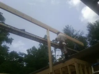 Carpenter setting a ridge beam over a new addition frame — Ice Dam Removal by Roofing Brothers in Morriston