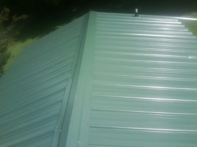 New green metal panels meeting at the ridge of a roof — Flat Roof Repair work by our crew in Morriston