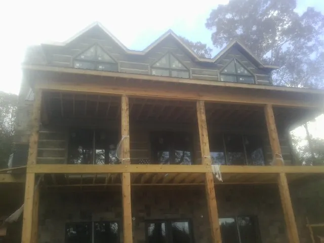 Dormers and porch framing on a large log home under construction — Roof Coating work by our crew in Morriston