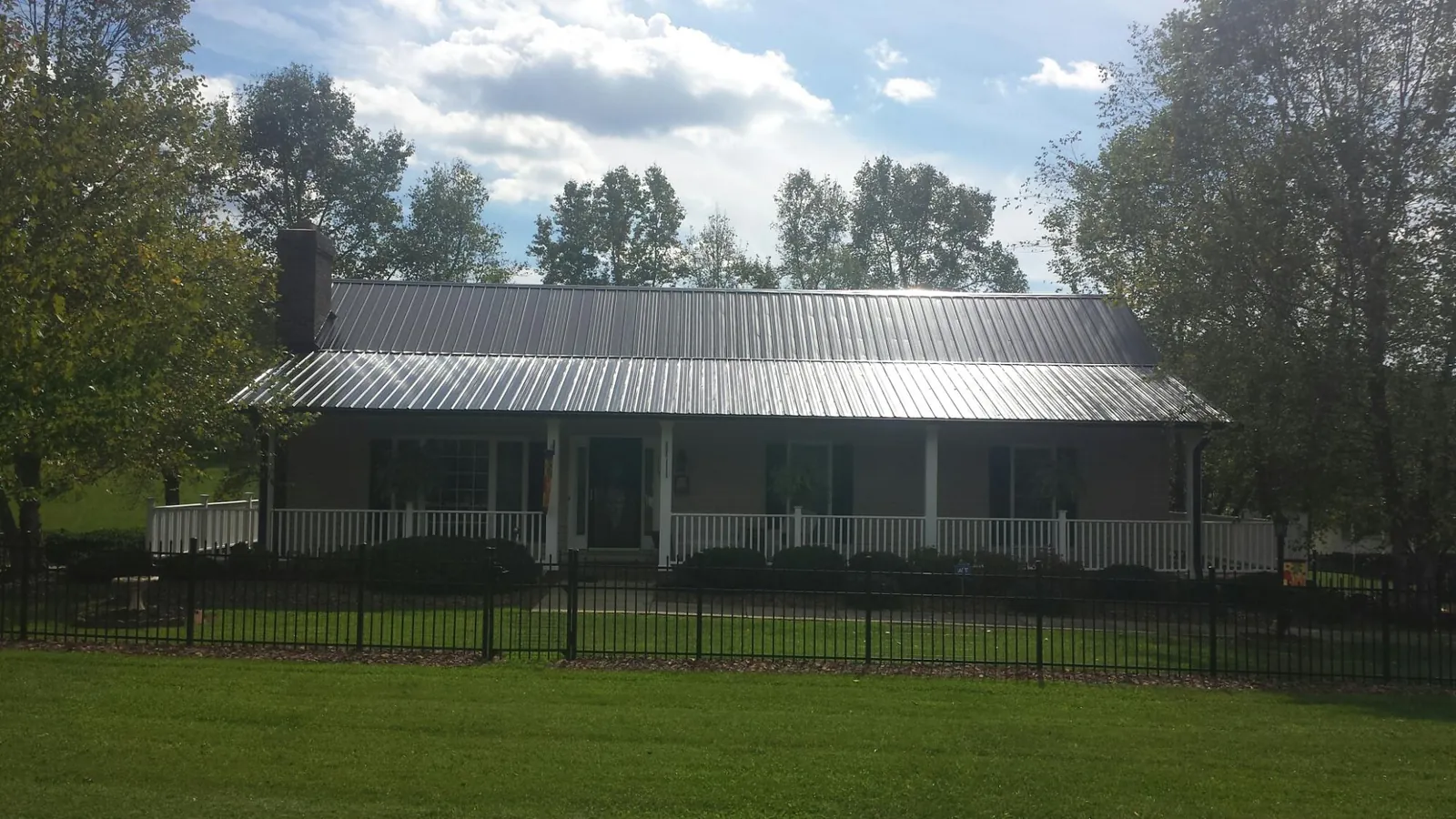 Gray metal roof on a brick ranch with a full width front porch — Gutter Guard Installation work by our crew in Morriston