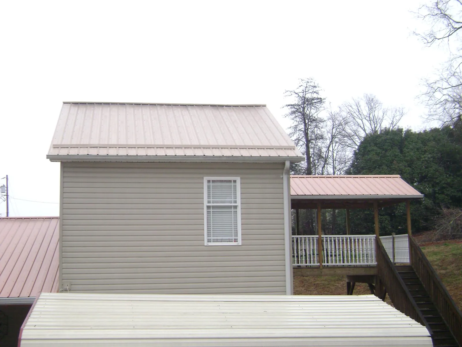 Tan metal roofs on a two story addition and attached porch, from a Roof Replacement job in Morriston