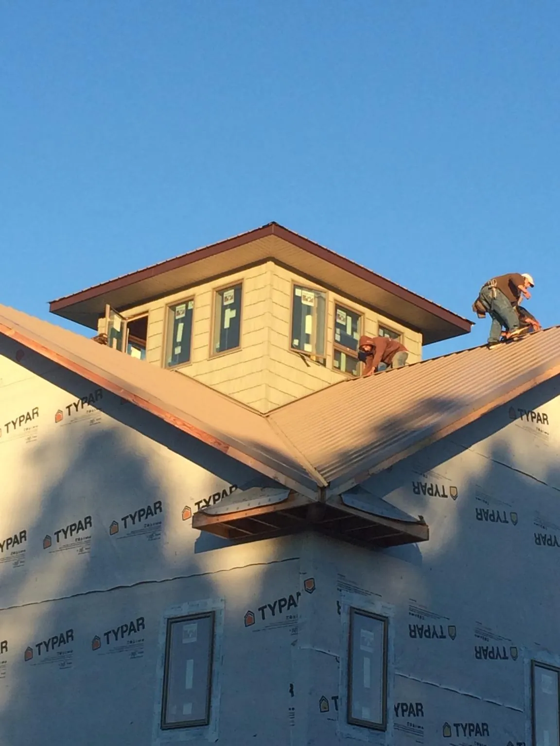Roofers working around a rooftop cupola on a new metal roof at sunset — Roof Waterproofing in Morriston by Roofing Brothers